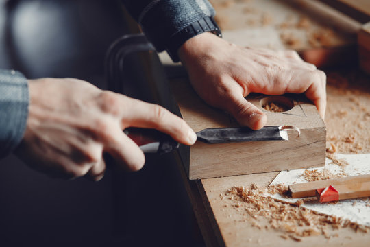 A man carves a tree. The carpenter works in a studio. An engineer provides a tree shape