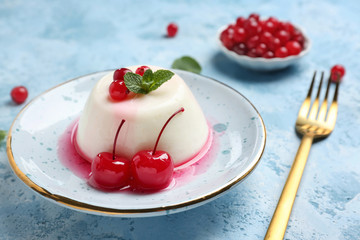 Plate with tasty panna cotta on color table