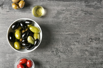 Tasty olives with oil on grey table