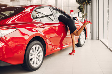 Woman buying the car. Lady in a car salon. Elegant black girl