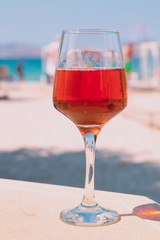 A glass of rose white on white sand beach, relaxation summer concept. Bright colors. 