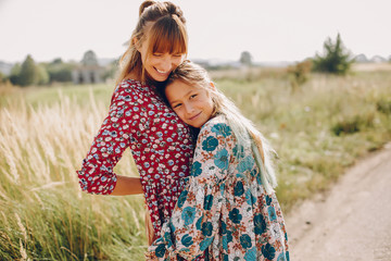 Fashionable mother with daughter. Family in a summer fiels. Girl in a red dress.