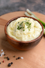 Bowl with tasty mashed potato on wooden board
