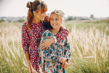 Fashionable mother with daughter. Family in a summer fiels. Girl in a red dress.