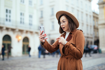 Happy woman greeting during a video call with a smart phone on the street