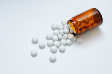 Yellow glass bottle with round pills on white background. Medical preparations.