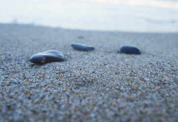 Fototapeta na wymiar Canary Islands nature. Black sea round stones on the sandy coast close up.