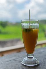 Mango papaya banana iced drink with rice fields in the background.
