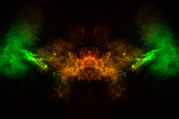 Abstract image of smoke of different green, yellow, orange and red colors in the form of horror in the shape of the head, face and eye on a black isolated background. Soul and ghost in mystical symbol
