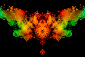 Smoke of different green, yellow, orange and red colors in the form of horror in the shape of the head, face and eye with wings on a black isolated background. Soul and ghost in mystical symbol