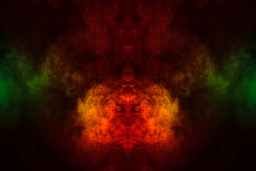 Abstract image of smoke of different green, yellow, orange and red colors in the form of horror in the shape of the head, face and eye on a black isolated background. Soul and ghost in mystical symbol