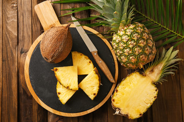 Composition with cut pineapples and coconut on wooden background