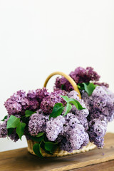 Perfect purple lilac flowers bunch in a basket on wooden table