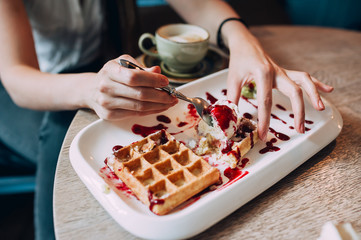 girl eating waffles with jam and ice cream. close-up