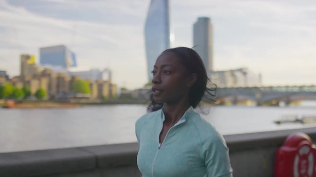 Young black female running by the riverside, in slow motion
