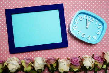 Mock up Empty Photo Frame and Alarm clock with roses flower decorate on pink polka dot background