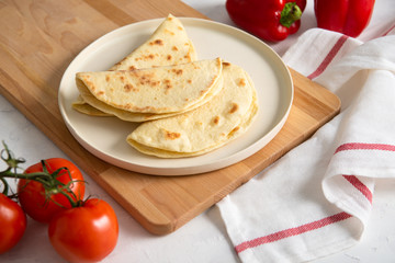 homemade italian piadina on a white plate with vegetables tomatoes and pepper on white background. Italian cuisine. Top view, copy space. flat lay