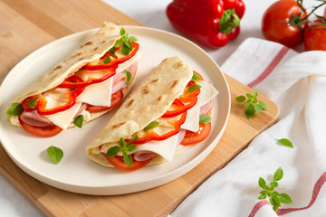 Fototapeta na wymiar Italian piadina on a white plate with vegetables tomatoes and pepper on white background. Italian cuisine. Side view, copy space.