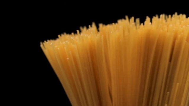 Raw spaghetti on black background slow motion.