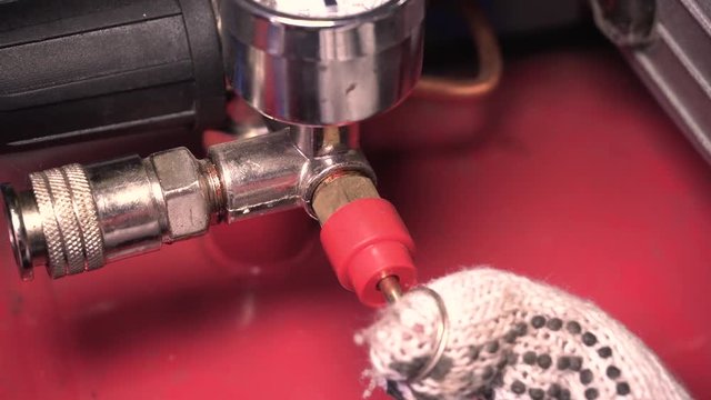 Bleeding compressed air from the receiver of the compressor, close up view at hand and manometer