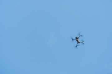 Professional filming drone flies in the air at a low altitude against a blue sky. Drone makes photos. Modern new technology
