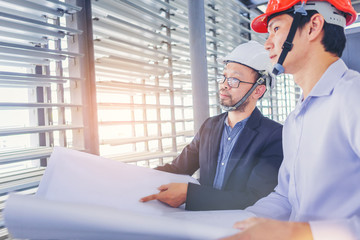 contractor and engineer with blueprints discuss at a modern construction site, Engineers in...