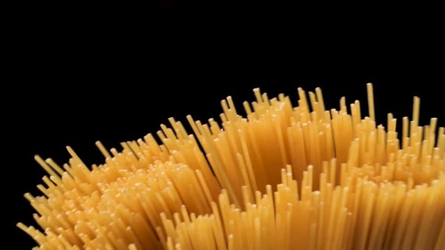Raw spaghetti on black background slow motion.