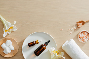 Spa still life top view with flowers, natural oil, bath salth and towels, spa skincare...