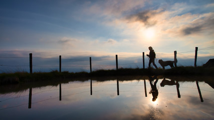 A woman on a mountain hike with her beloved dog at sunset