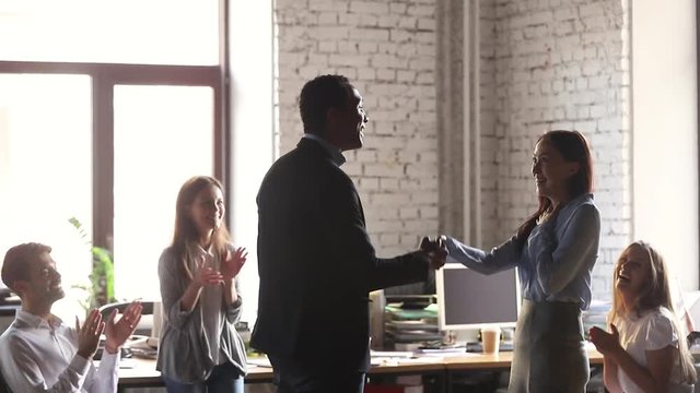 Helpful african american male boss handshake congratulate happy female employee