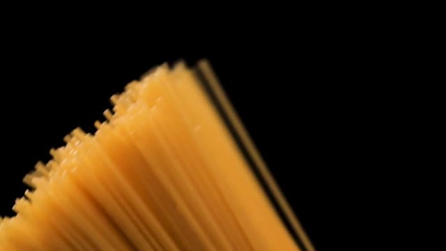 Raw spaghetti on black background slow motion.