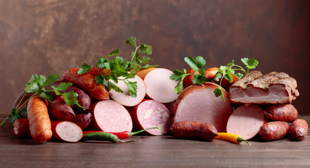 Different sausages, bacon and smoked meats on a  wooden table.