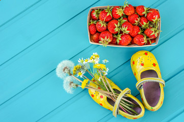 Summer background with strawberries, flowers and tiny baby shoes