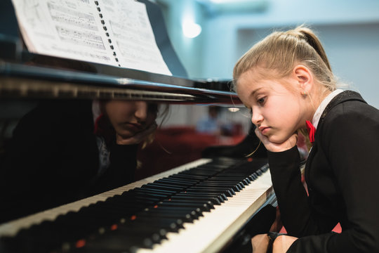 disappointed little girl trying to teach to play piano