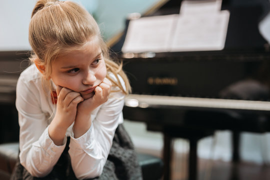 portrait of disappointed little girl trying to play piano