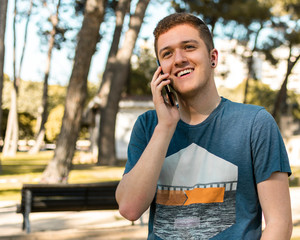 Handsome teenager talking on a mobile phone outdoors.