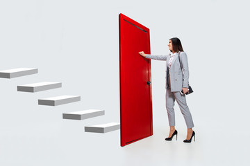 Knocking in emptiness. Young woman in grey suit trying to open the red door in career ladder, but...