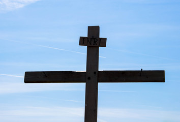 Wooden cross in silhouette on background of blue sky