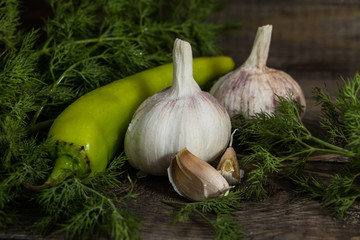 Garlic, green hot pepper with dill on a wooden table