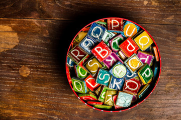 Tin can full of colorful ceramic tiles with letters