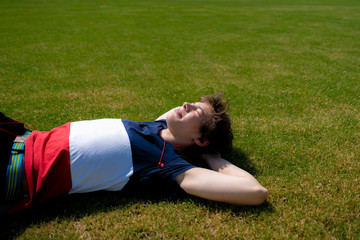 young man relax chill outdoor on the green grass lawn under the summer sunshines