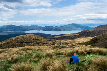 Two hikers looking at view of lake Rotoaira and lake Taupo from Tongariro Alpine Crossing hike with...