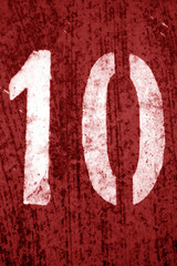 Number 10 in stencil on metal wall in red tone.