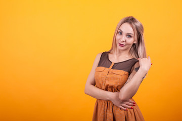 Obraz premium Pretty young woman smilling at the camera in casual dress over yellow background