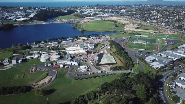 Wide aerial view of Rosedale Water Treatment Plant and suburban neighborhoods and football fields of Auckland, New Zealand