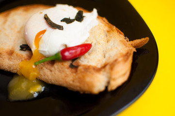  egg poached on a black plate on a yellow background breakfast