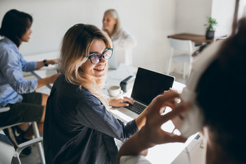 Freelance female web-developer having fun in office and joking with co-workers. Attractive blonde...