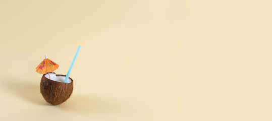 Relax, vacation, travel concept banner. Fresh Coconut cocktail with umbrella and straw on yellow...