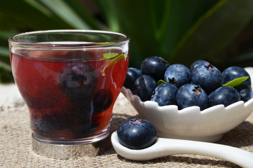 Blueberry tea in a glass cup and fresh blueberries on the table in the garden.Natural herbal summer beverage.Selective focus.