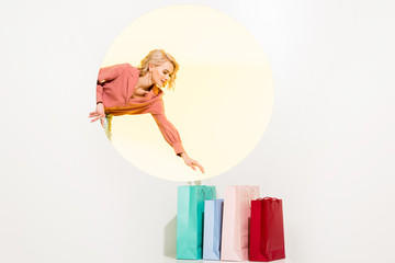 beautiful stylish girl posing with colorful shopping bags on white with yellow circle